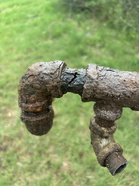 Severely corroded exterior plumbing pipe removed for replacement