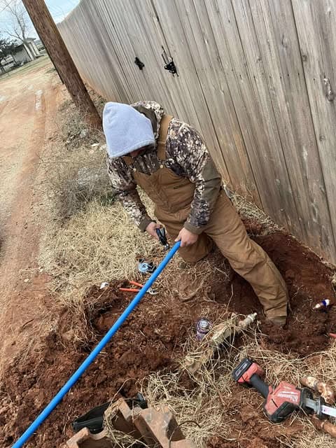 Plumber working on an exposed blue exterior water line