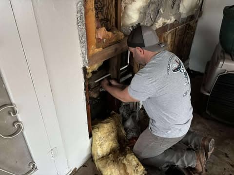 F5 plumber working beside exposed plumbing inside a wall