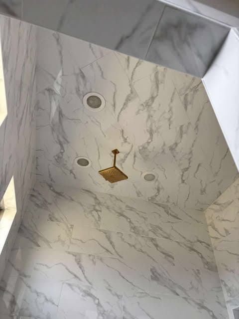 Finished marble-look shower with gold plumbing fixtures