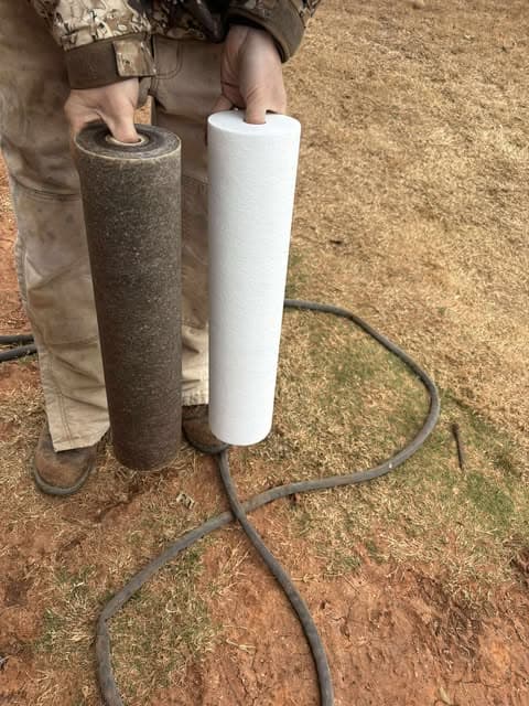 Used dark water filter cartridge held beside a clean replacement cartridge